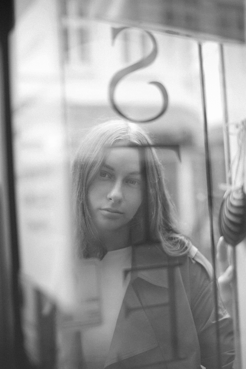 A girl looking through a shop window seen from the inside