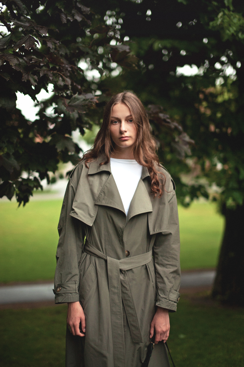 A girl standing in the park in front of a tree