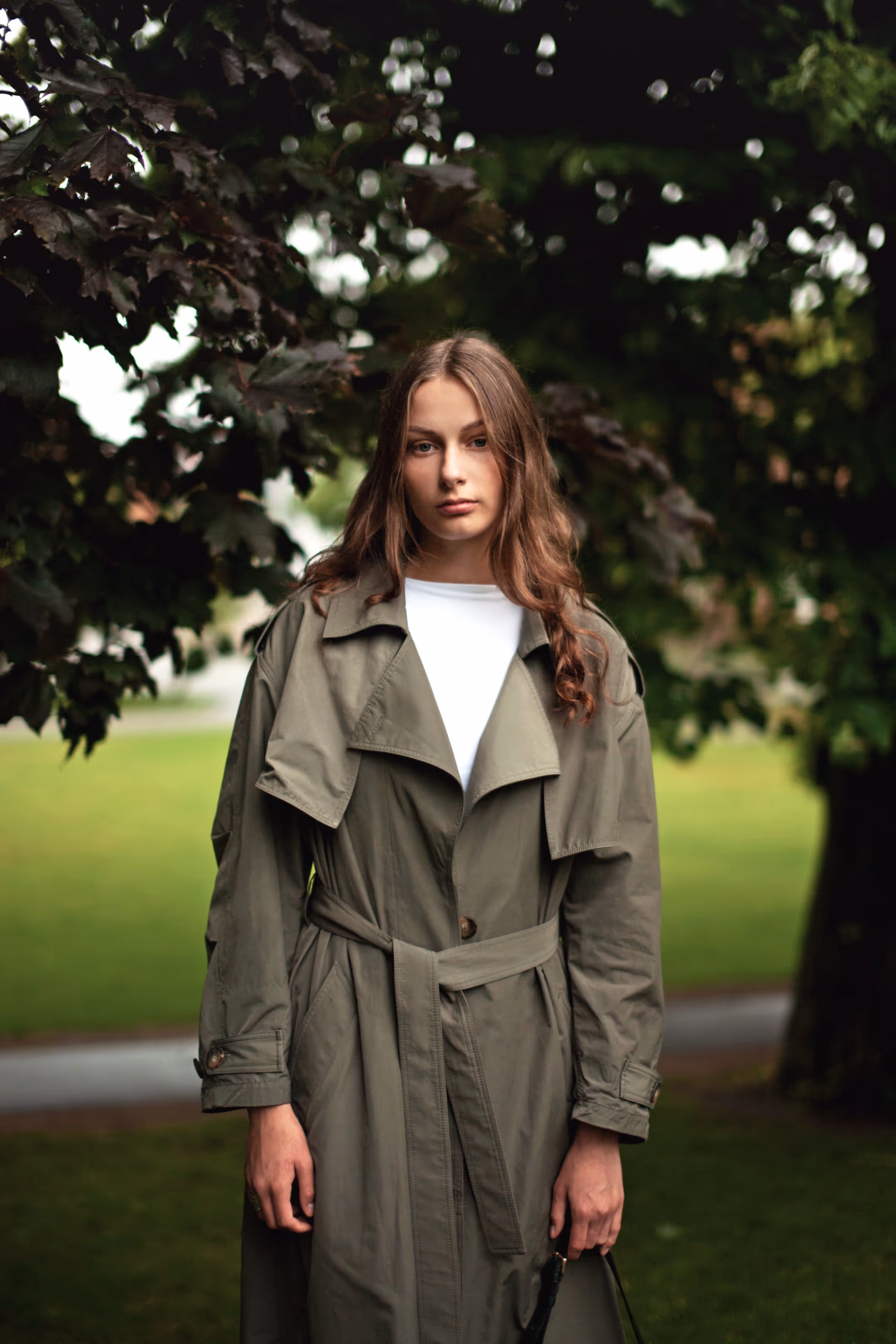 A girl standing in the park in front of a tree