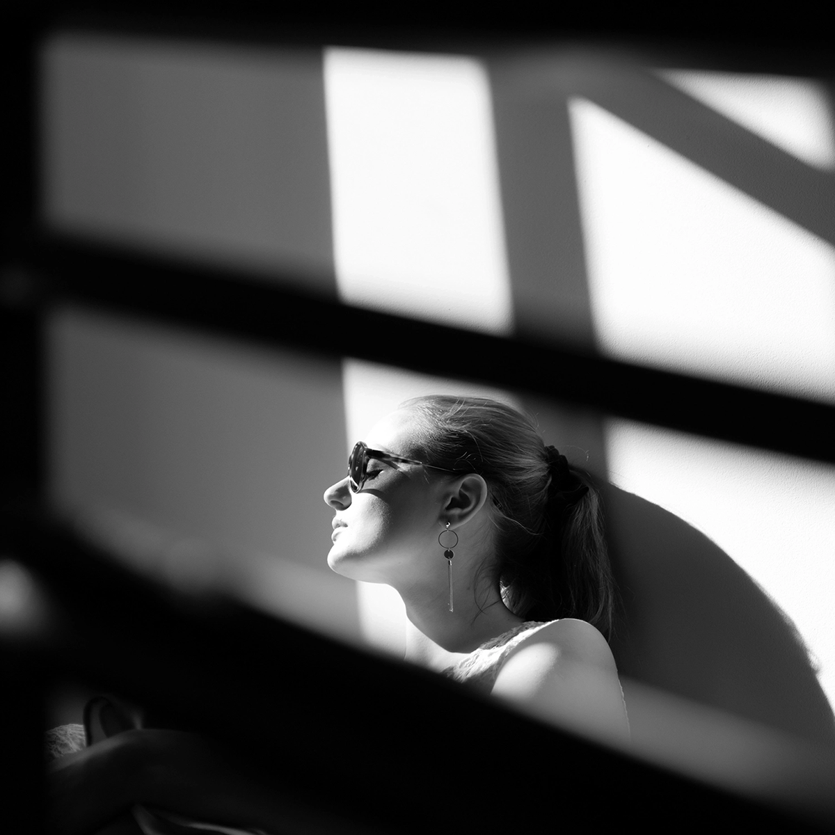 A girl wearing glasses leaning against a wall