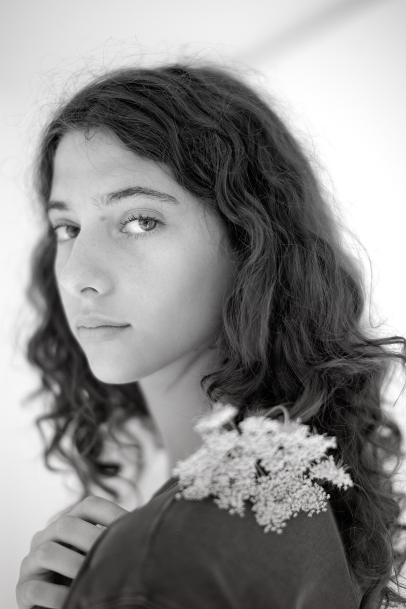 A girl with a white flower looking over her shoulder