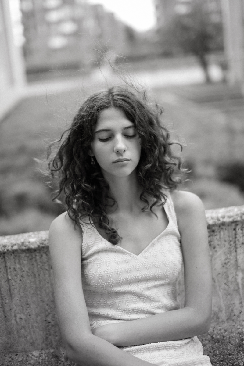 A girl with closed eyes sitting on a stone bench