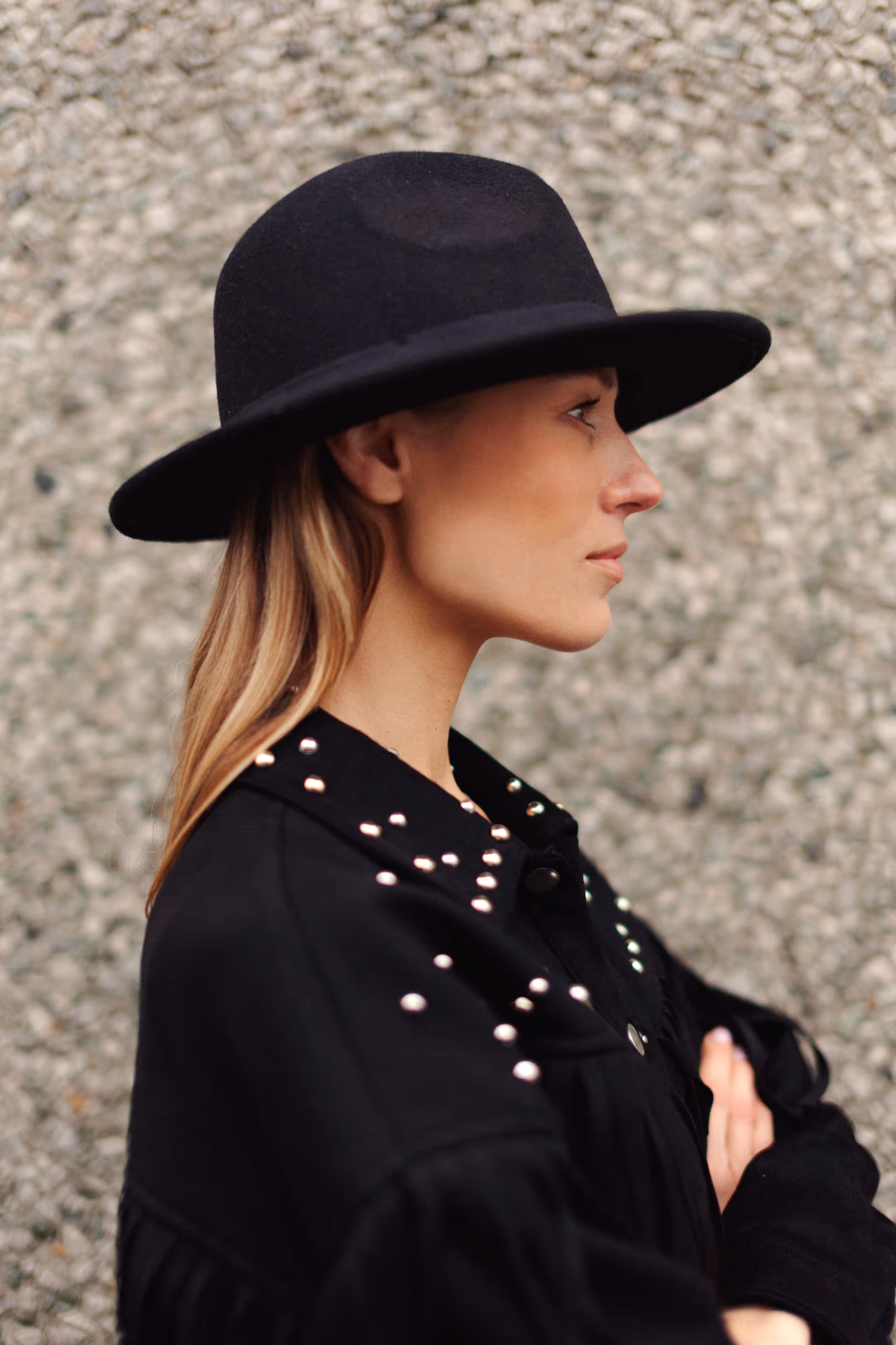 A profile shot of a woman in a hat with her arms crossed over her chest.