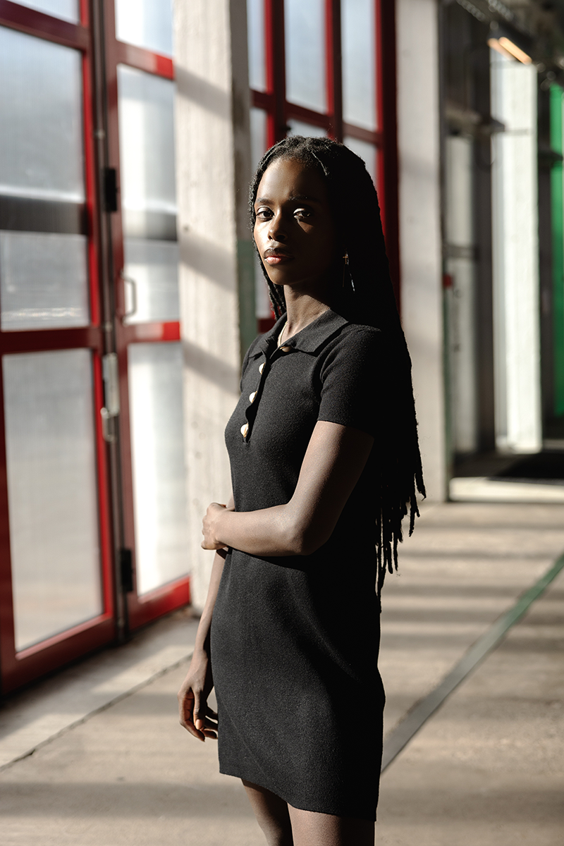 A woman in a black dress standing in an industrial hall