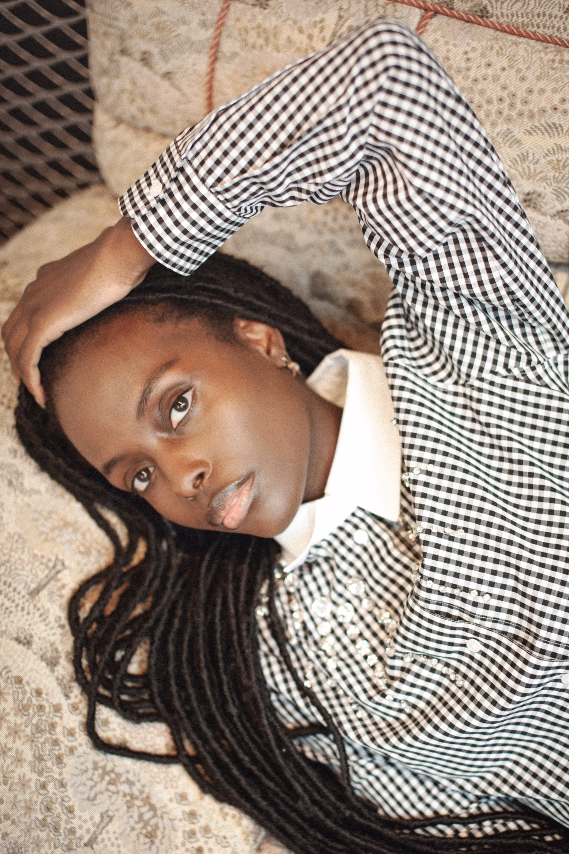 A woman in a checkered shirt lying on a sofa with her hand on her head