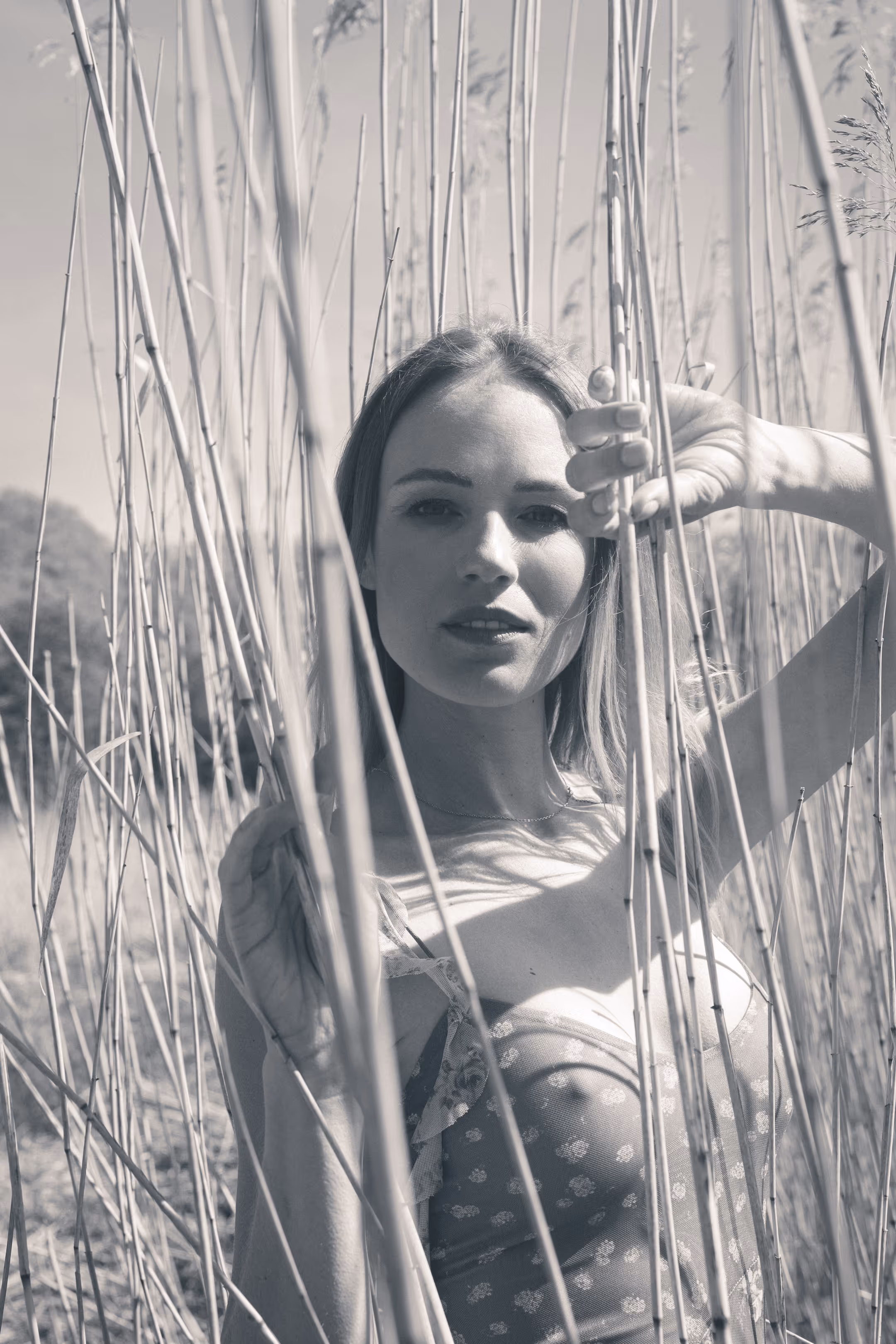 A woman in a dress among dried grasses.