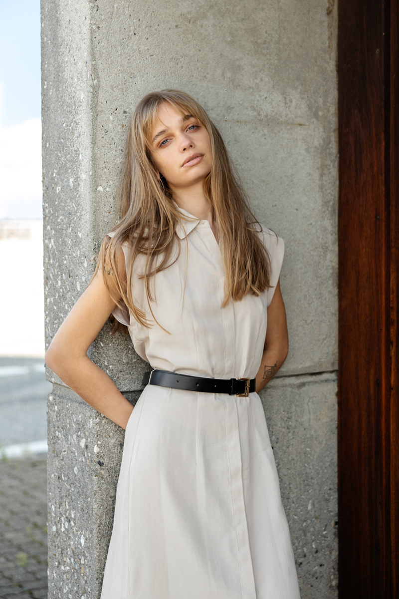 A woman in a dress leaning her back against a townhouse door frame