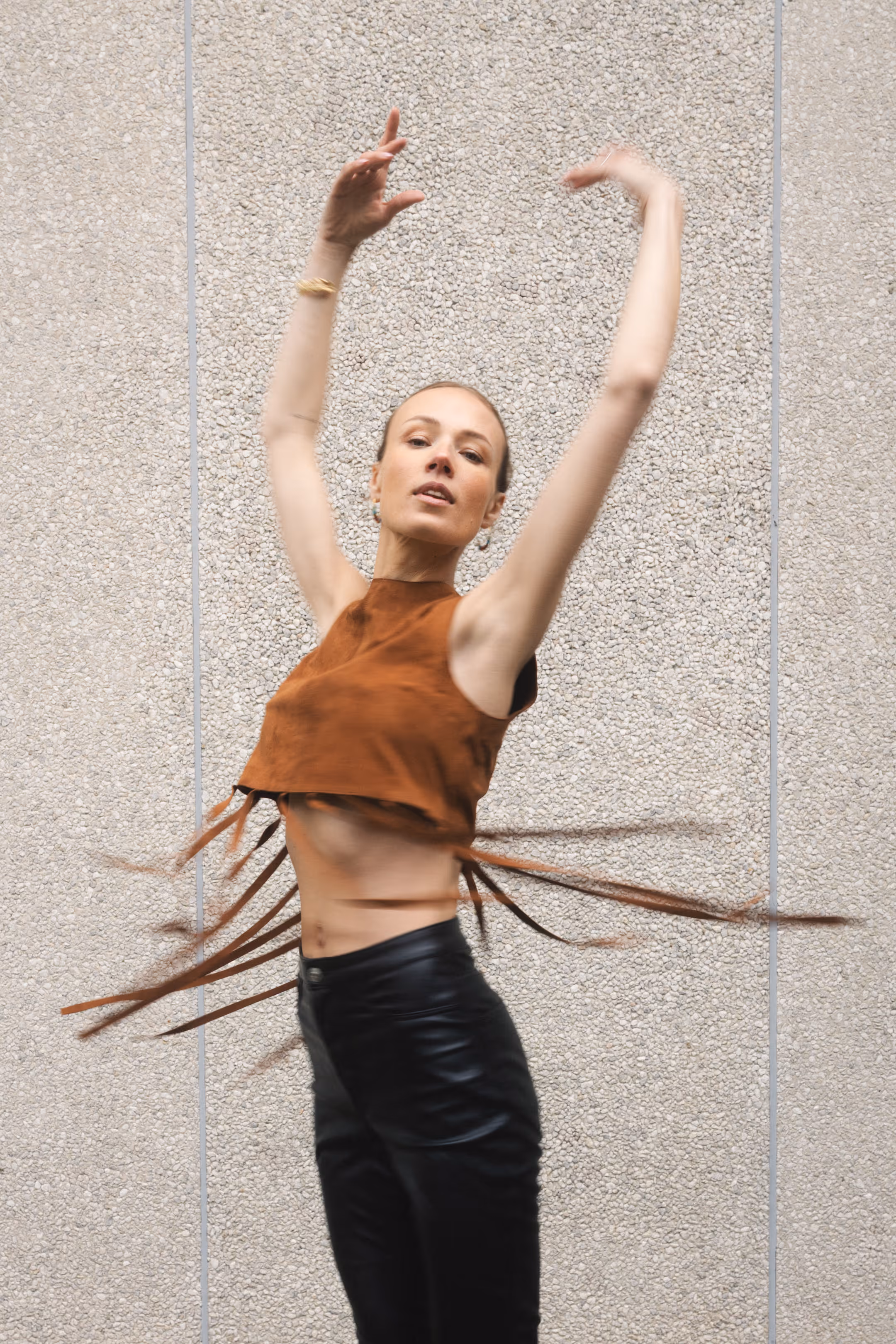 A woman in a fringed top in an artistic, dance-like pose.