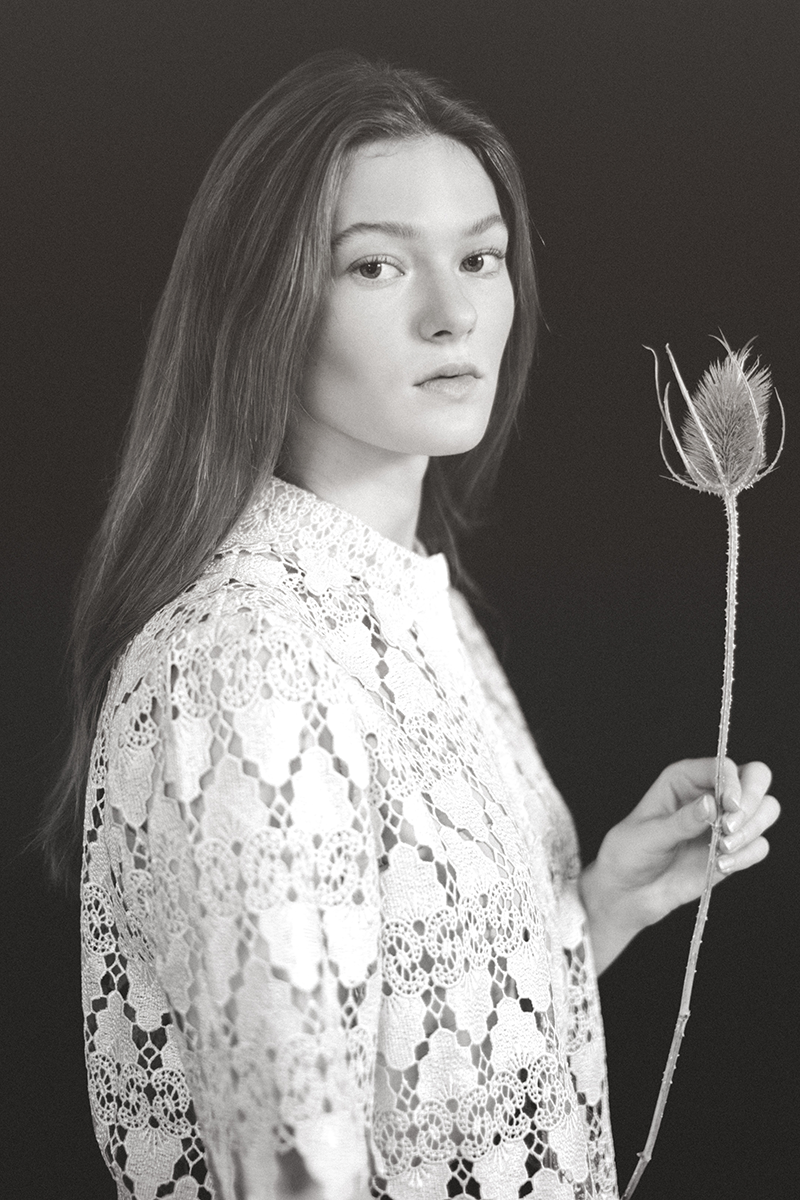 A woman in an embroidered blouse holding a dried Cardistelli flower