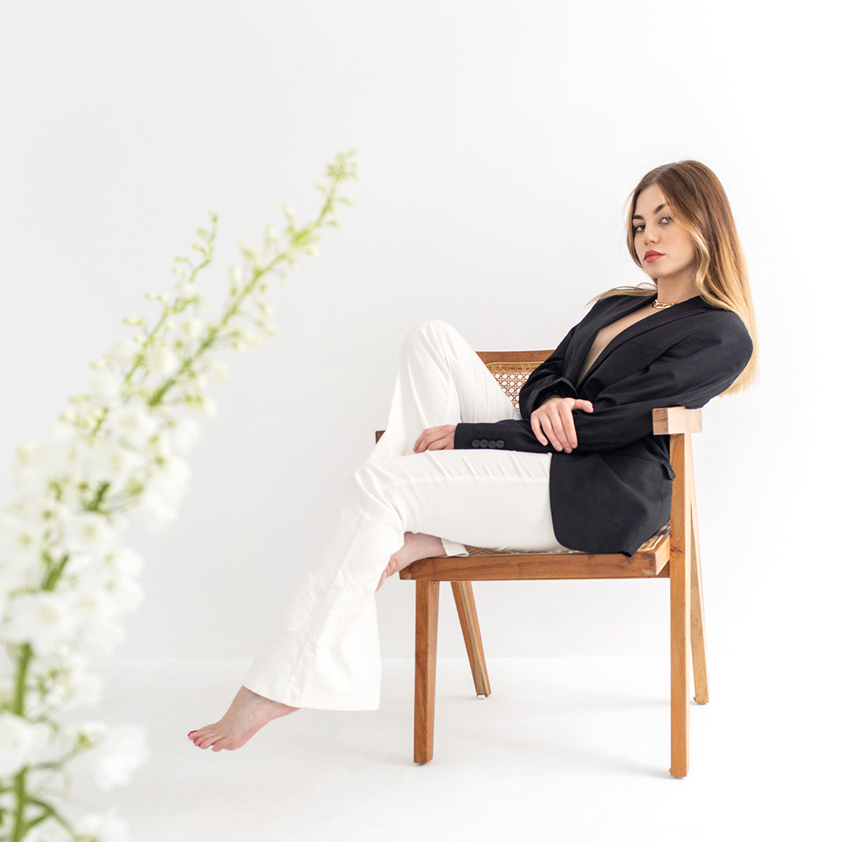 A woman sitting sideways on a chair against a white background