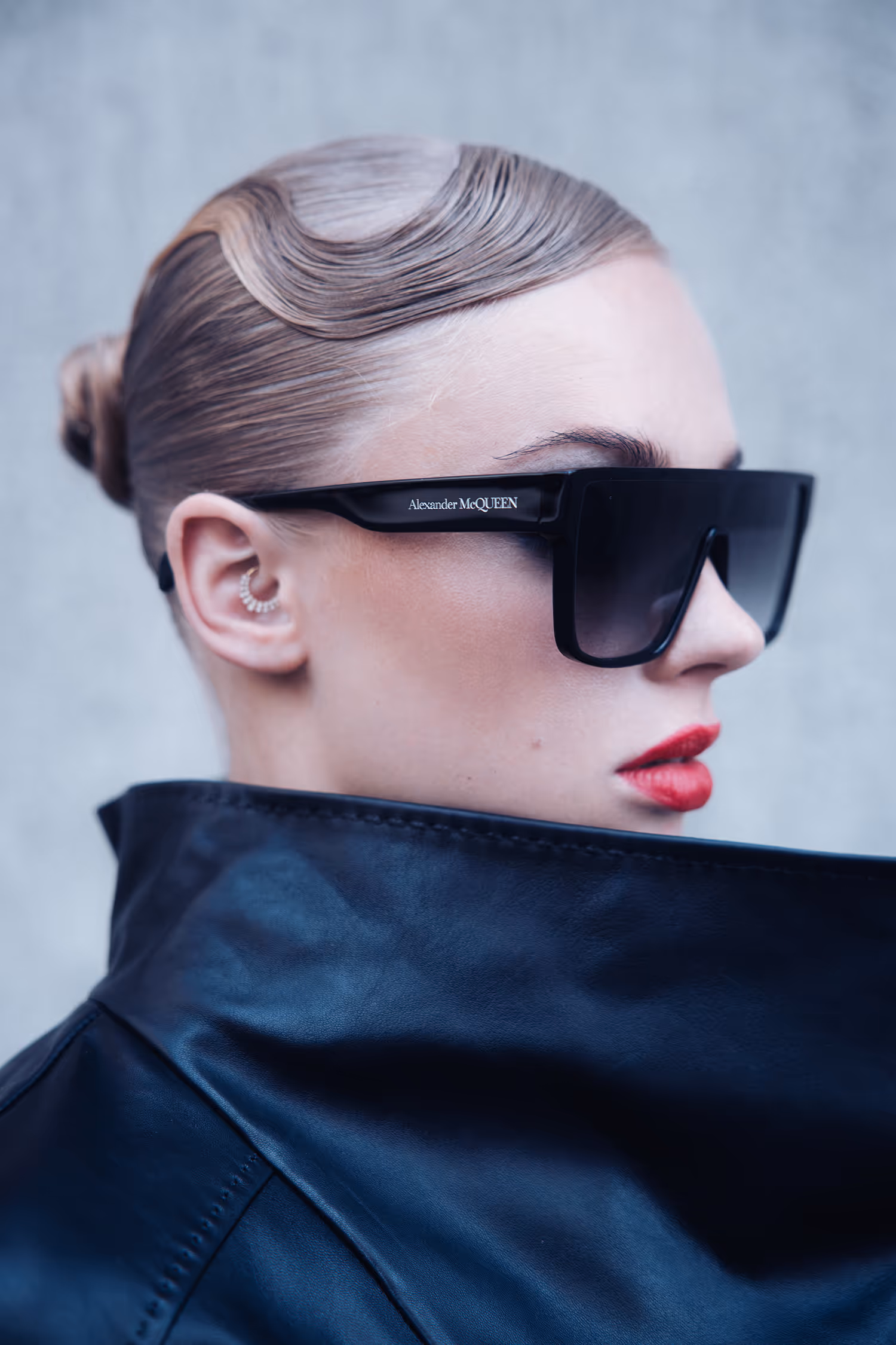 Woman in sunglasses covering her chin with the collar of a black leather jacket
