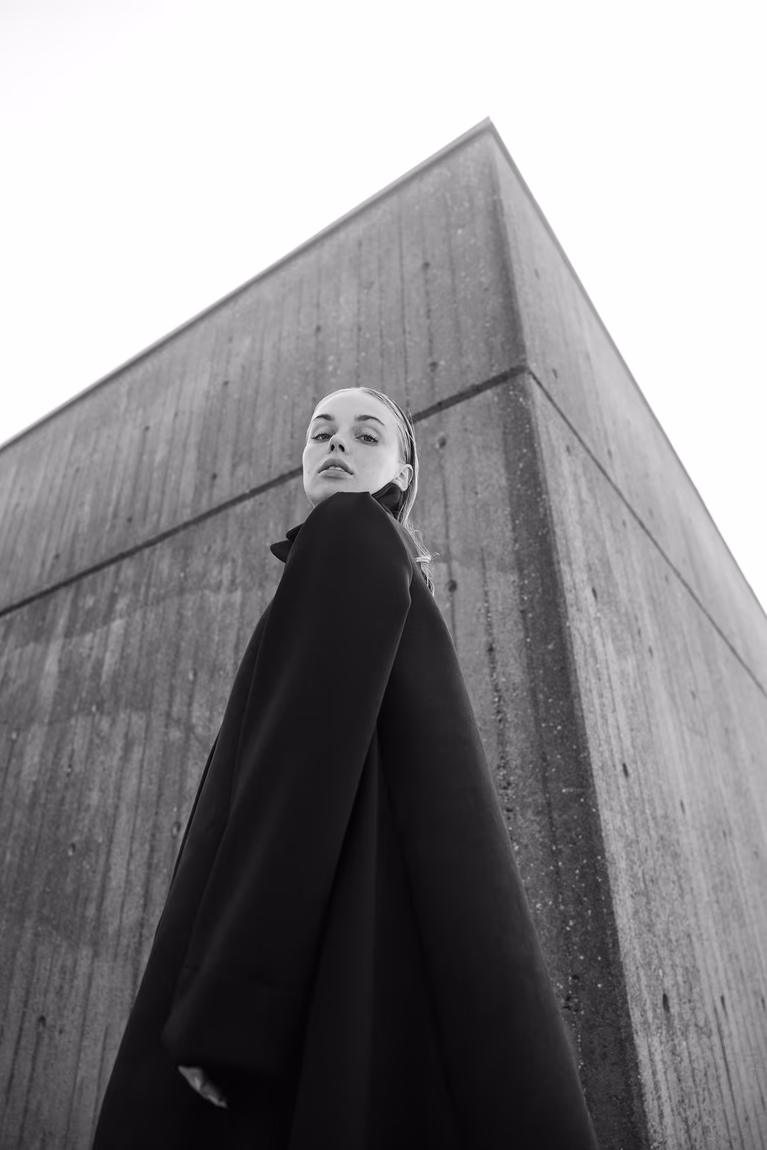 Woman against the corner of a building looking back