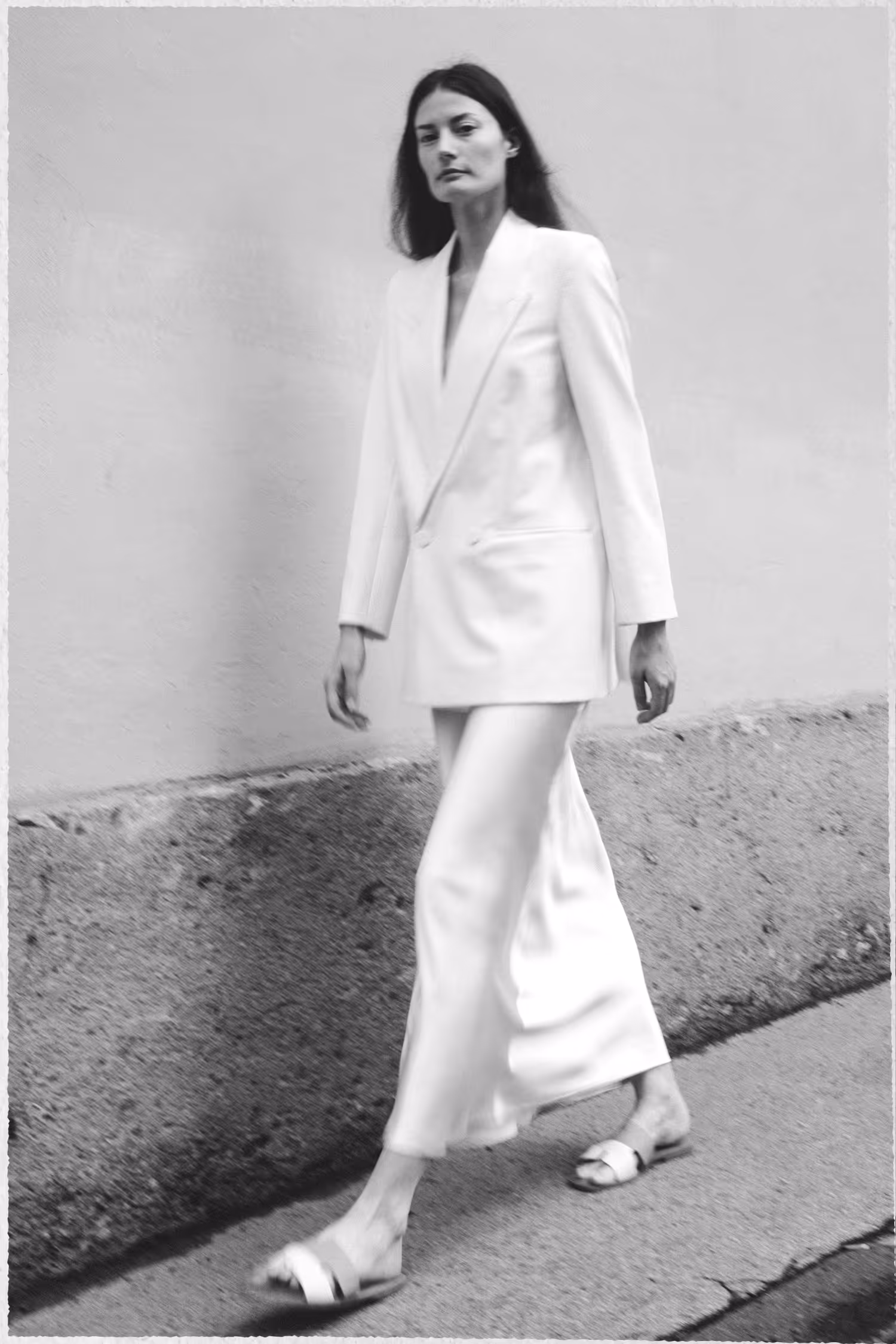 A woman dressed in white walking by the wall