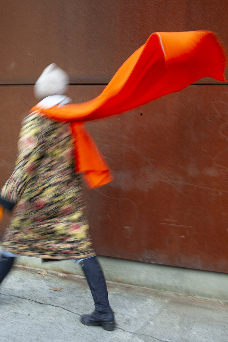 Woman walking down the street with a fluttering scarf