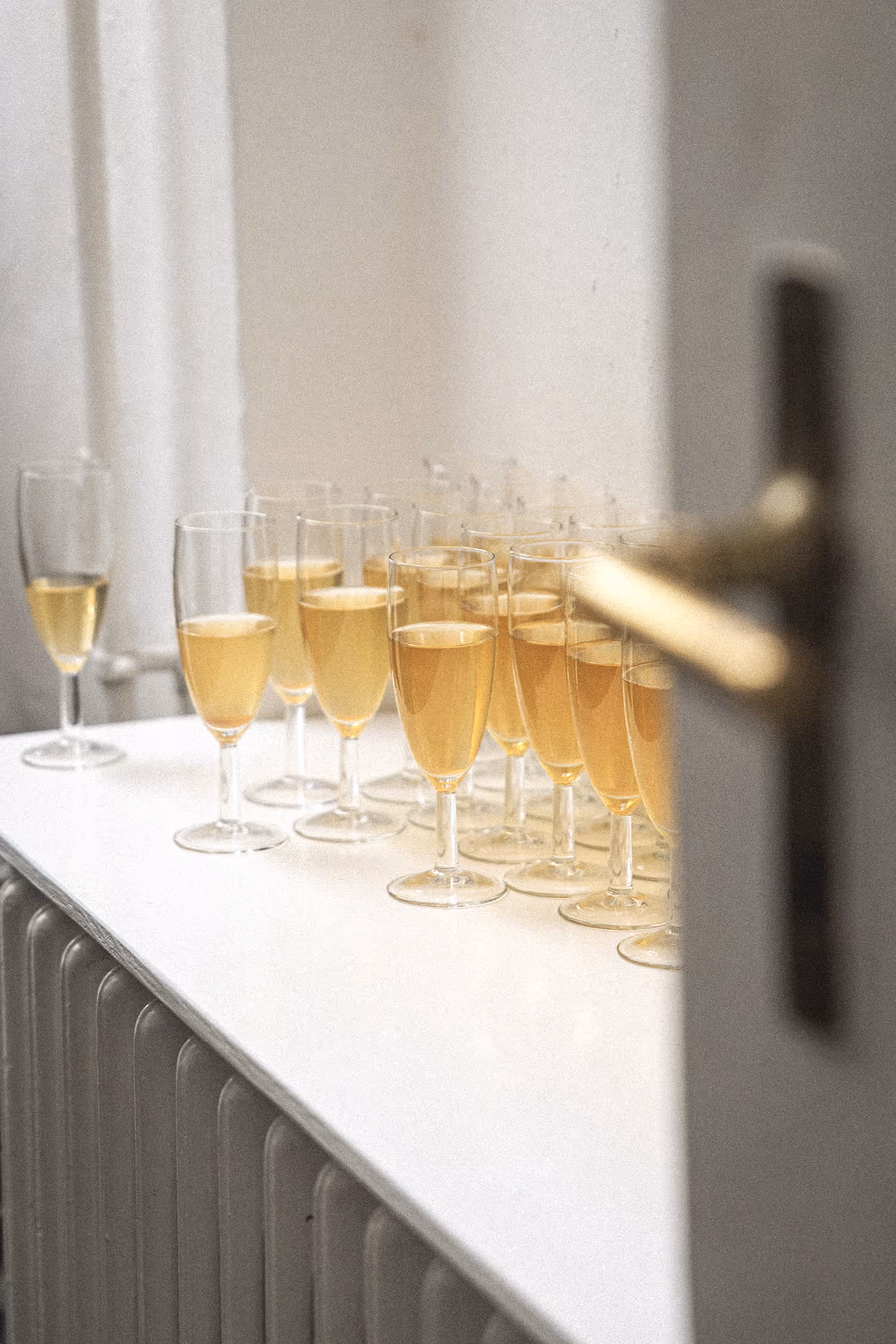 Soft-focus, high-key photograph of champagne glasses lined up at the Copenhagen Fashion Week 2025 backstage, featuring cinematic depth and light.