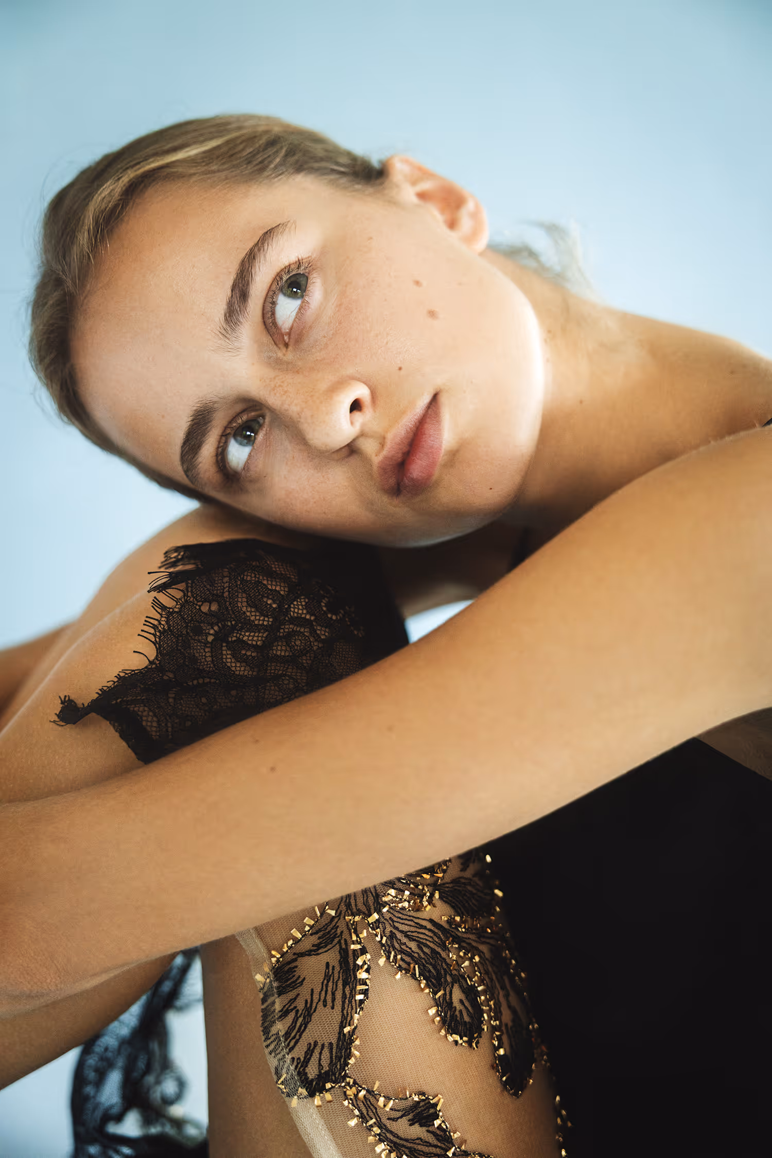 Intimate fashion portrait in Vejle using soft natural light, capturing a model in black lace with raw, natural makeup and texture details.